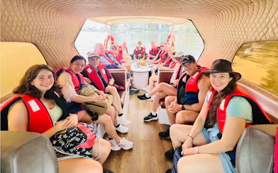 Group on speed boat for VIP Cu Chi Tunnels tour, wearing life jackets, river view in background.