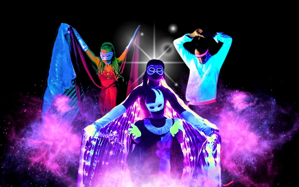 Artists performing in vibrant black light theatre, Prague.
