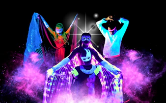 Artists performing in vibrant black light theatre, Prague.