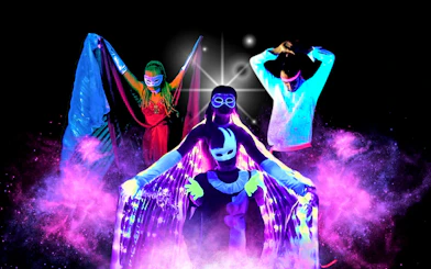 Artists performing in vibrant black light theatre, Prague.