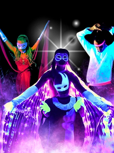 Artists performing in vibrant black light theatre, Prague.