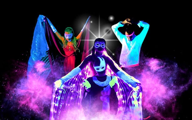 Artists performing in vibrant black light theatre, Prague.