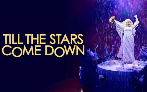 Performer in white dress on stage with audience, "Till The Stars Come Down" show.