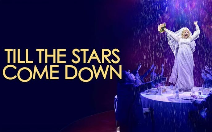 Performer in white dress on stage with audience, "Till The Stars Come Down" show.