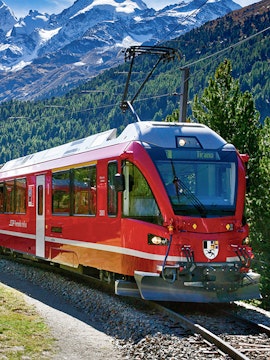 Red train traveling through Swiss Alps on Grindelwald to Jungfraujoch route.