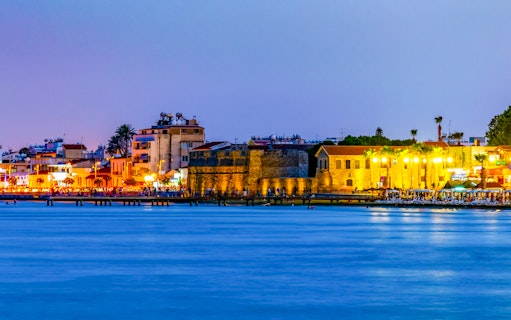 Larnaca waterfront at sunset with historic buildings and vibrant lights.