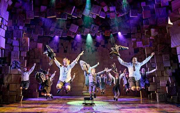 Performers jumping energetically on stage during Matilda The Musical.
