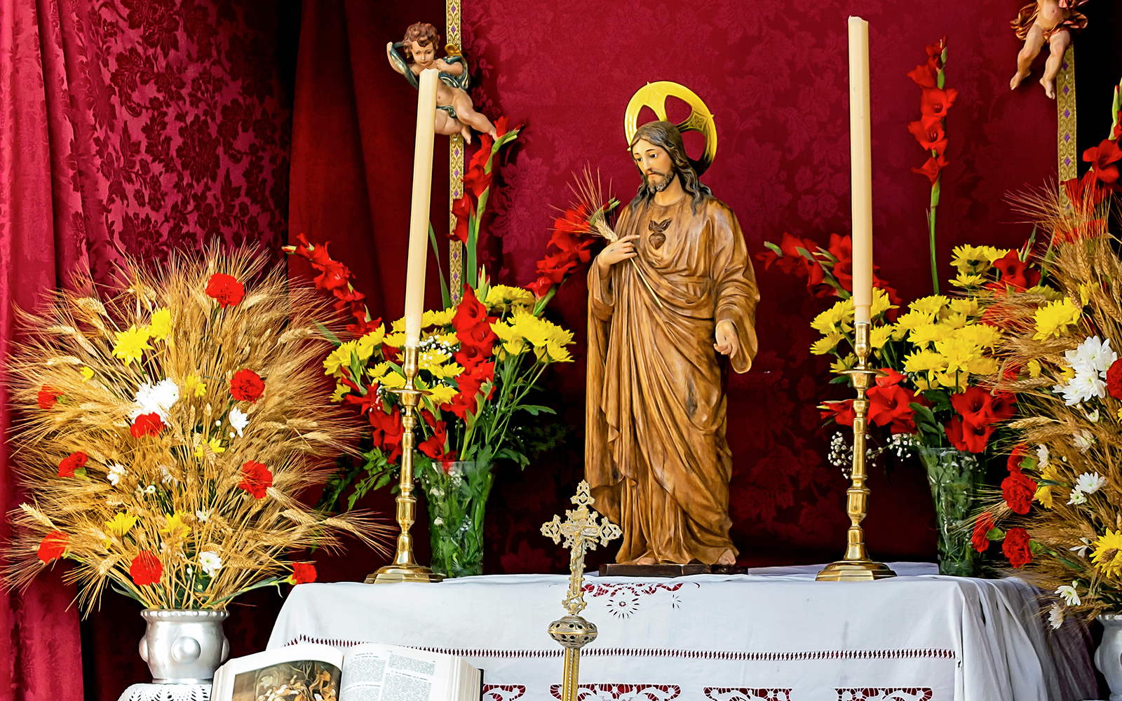 Statue of Jesus with flowers and candles during Corpus Christi festival in Spain.