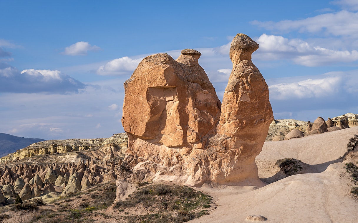 Fairy chimneys and Camel Rock in Devrent Valley, Cappadocia under a blue sky.