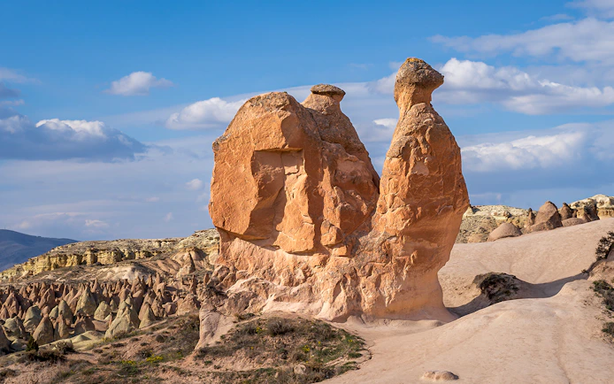 Fairy chimneys and Camel Rock in Devrent Valley, Cappadocia under a blue sky.
