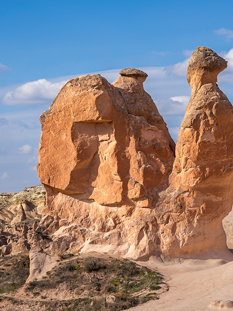 Fairy chimneys and Camel Rock in Devrent Valley, Cappadocia under a blue sky.