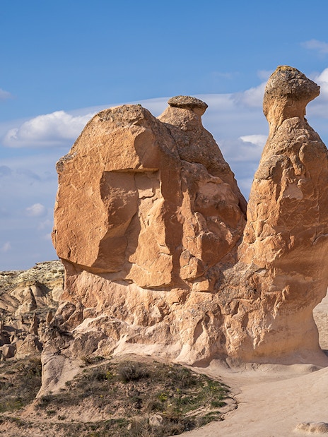 Fairy chimneys and Camel Rock in Devrent Valley, Cappadocia under a blue sky.