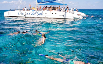 Snorkelers near a catamaran at Ile aux Cerf, Mauritius, enjoying water activities.