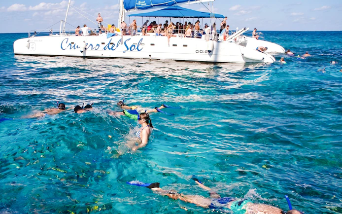 Snorkelers near a catamaran at Ile aux Cerf, Mauritius, enjoying water activities.
