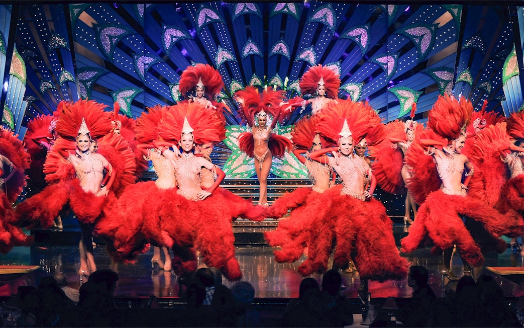 Performers in red feather costumes at Moulin Rouge show, Paris stage.