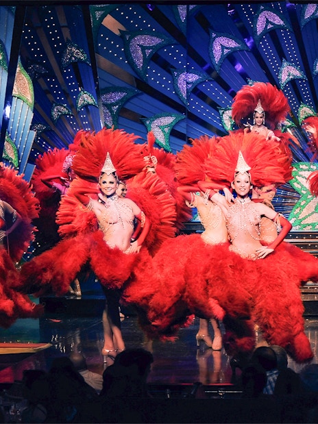 Performers in red feather costumes at Moulin Rouge show, Paris stage.