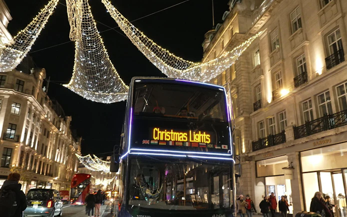 London night bus under Christmas lights on a festive street.