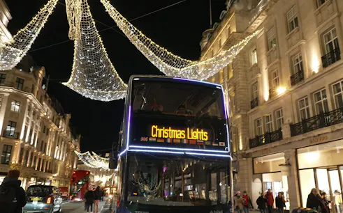 London night bus under Christmas lights on a festive street.