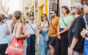 Group of tourists on a guided food tour in a Paris street.