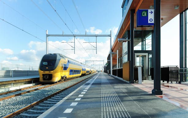 High-speed train passing through a modern European station platform.