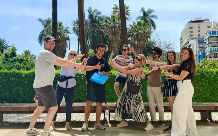 Group enjoying a guided tour in Málaga with palm trees and cityscape in the background.