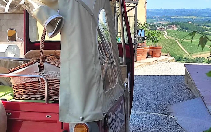 Tuk Tuk with picnic basket overlooking Tuscany vineyards.