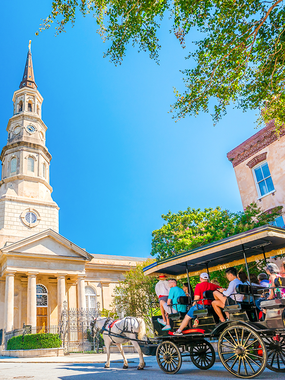 Horse-drawn carriage tour in front of historic church in downtown Charleston.