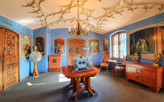 Interior room of Hohenschwangau Castle in Bavaria with ornate ceiling and historical paintings.