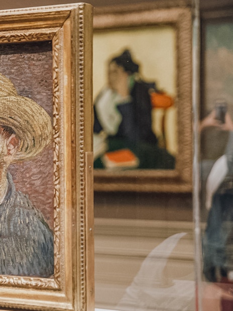 Van Gogh self-portrait with straw hat displayed in museum exhibit.