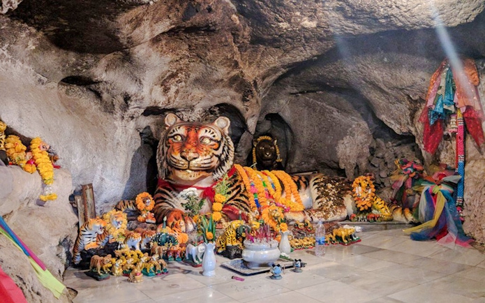 Tiger statue adorned with garlands inside Tiger Cave Temple, Krabi.