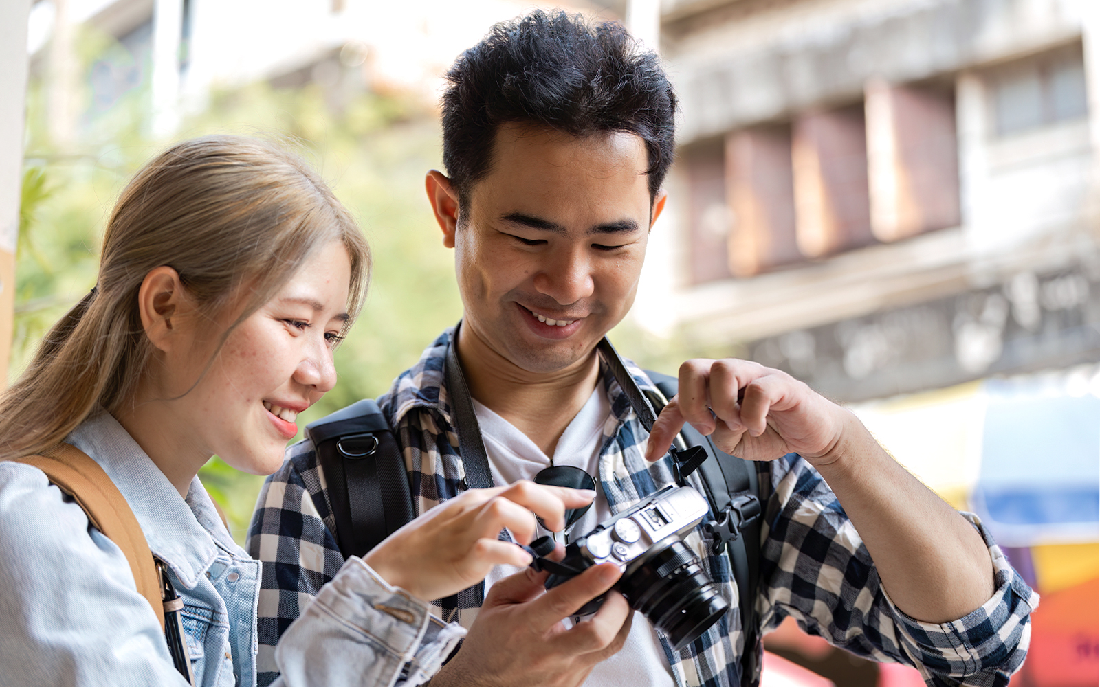 Man and woman examining a camera together outdoors.