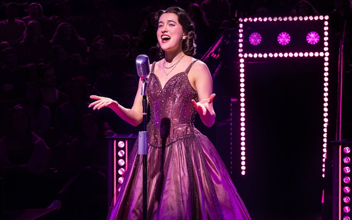 Singer performing on stage with vintage microphone, surrounded by purple lights.