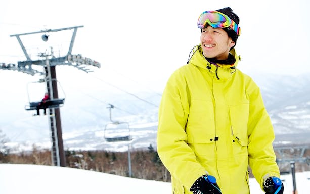 Skier at Tomamu Ski Resort with chairlift in background, Hokkaido, Japan.