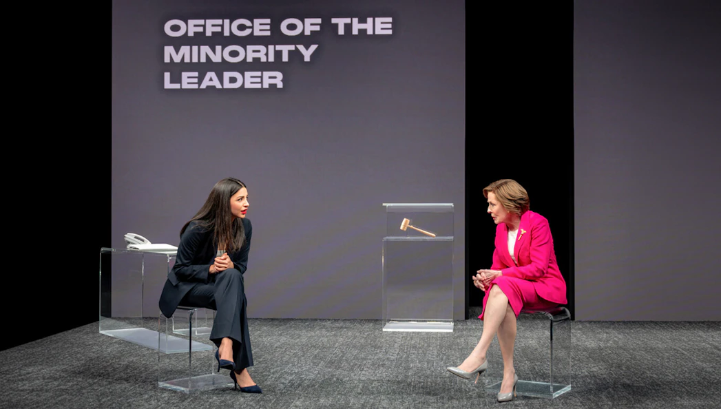 Two actors in a play set in the Office of the Minority Leader, engaged in a conversation.