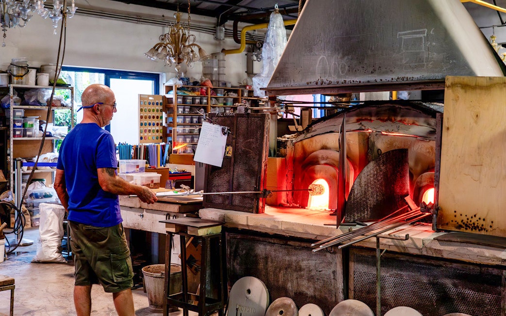 Glassblower working at furnace in Murano workshop.