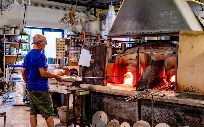 Glassblower working at furnace in Murano workshop.