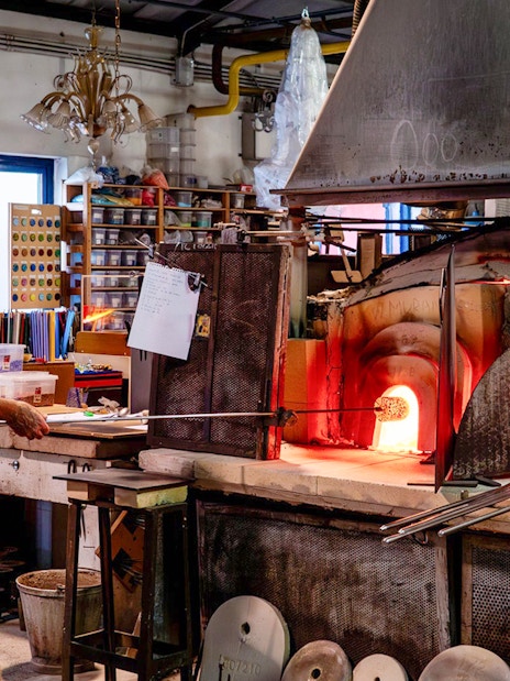 Glassblower working at furnace in Murano workshop.
