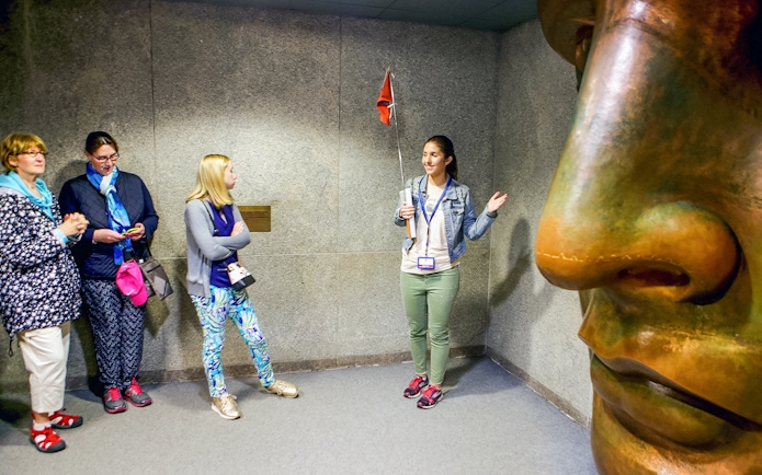 Guide explaining to tourists inside the Statue of Liberty museum.