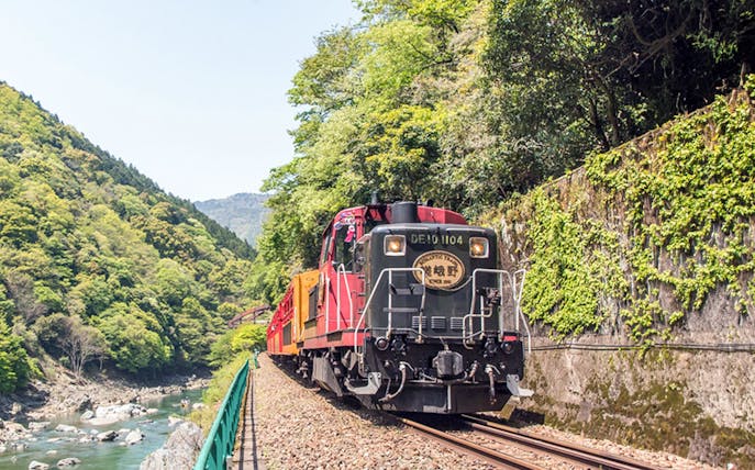 Sagano Romantic Train traveling through lush green mountains in Kyoto, Japan.