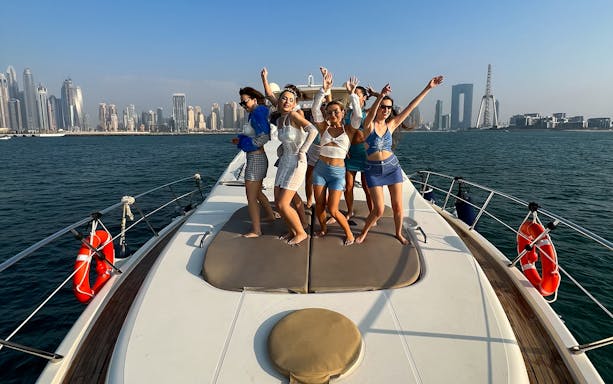 Group enjoying a luxury yacht cruise with Dubai skyline in the background.