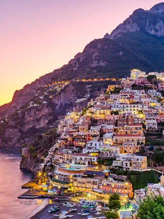 Positano hillside with colorful buildings at sunset, part of Rome to Positano tours.