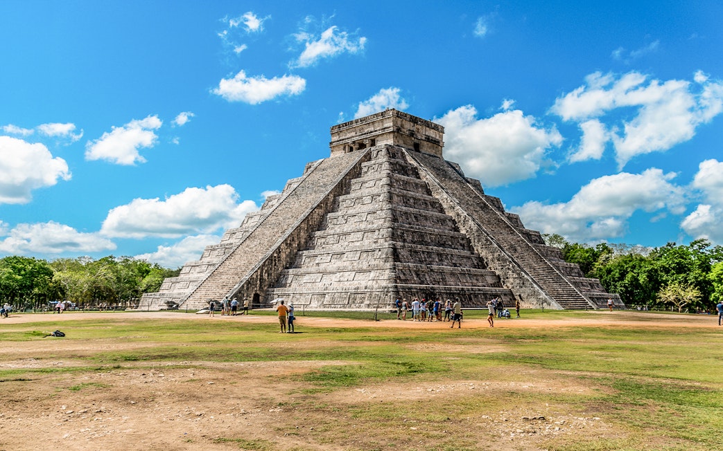 Chichen Itza pyramid with tourists exploring the site in Mexico.