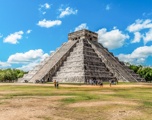 Chichen Itza pyramid with tourists exploring the site in Mexico.