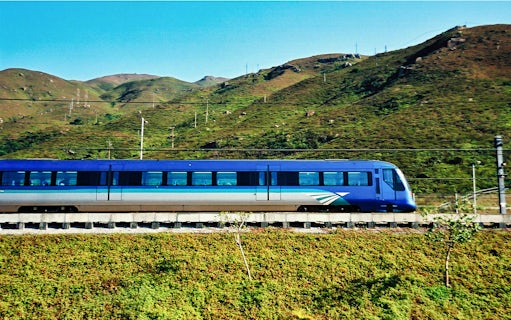 Airport Express train traveling through green hills in Hong Kong.