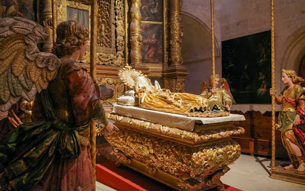 Religious statues in Palma Cathedral depicting angels around a golden altar.