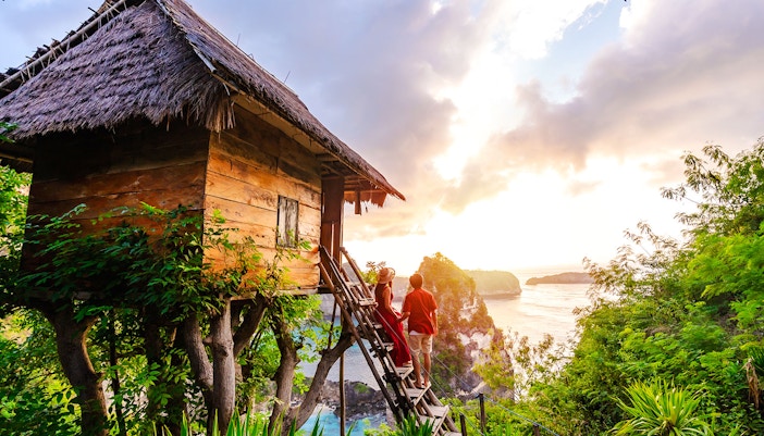 Tree house overlooking ocean cliffs at sunset in Nusa Penida.