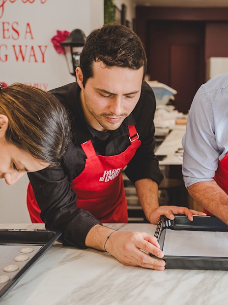 Participants piping macarons in a Paris workshop.