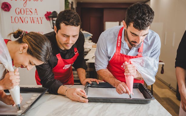Participants piping macarons in a Paris workshop.