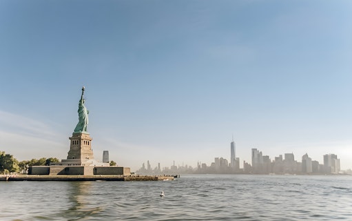 Statue of Liberty with New York City skyline, view from ferry to Ellis Island.