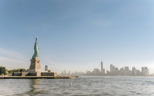 Statue of Liberty with New York City skyline, view from ferry to Ellis Island.